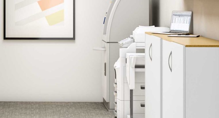 White printer in modern office resource area with grey carpet and framed art on the wall